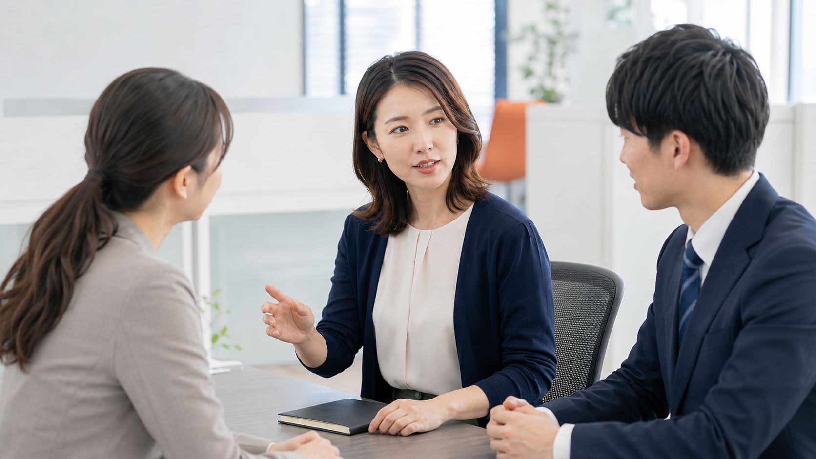 業務推進・会計事務スタッフが同僚から相談を受けて次の進め方を共有する様子